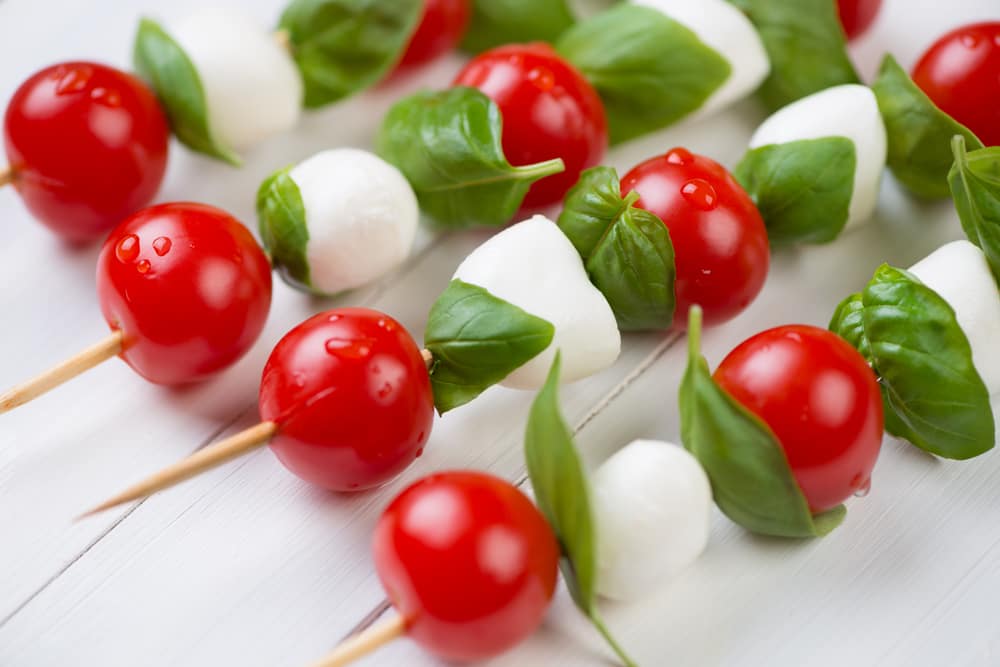 Entre los snacks saludables para picar sin pecar, están las brochetas de queso mozzarella, tomates cherry y hojas de albahaca..